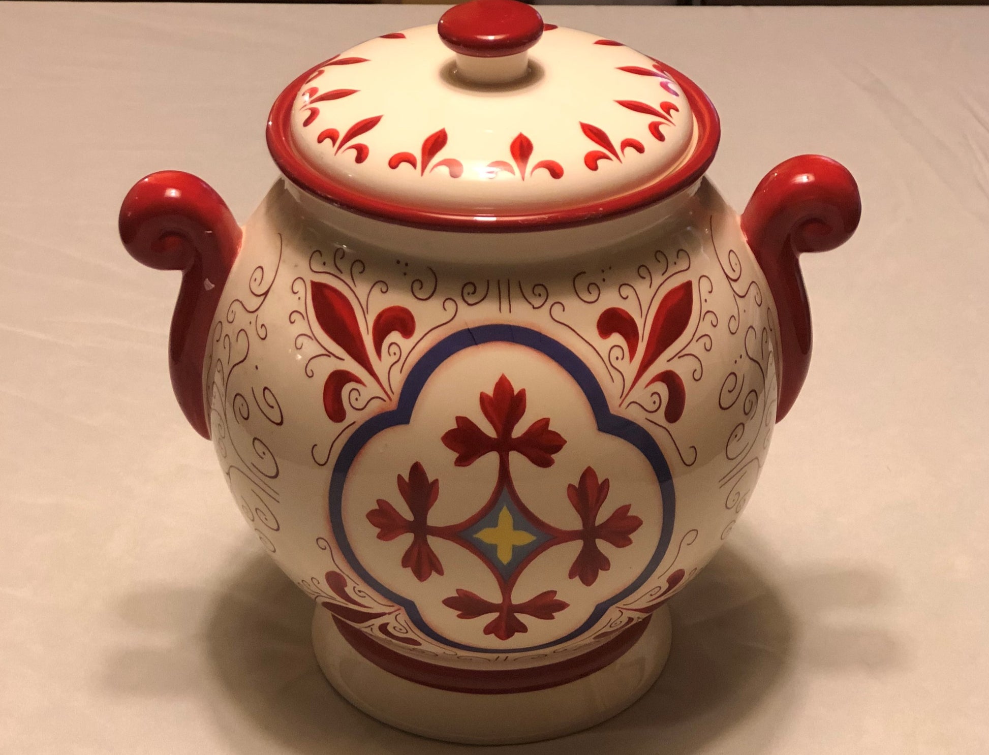 Decorative Red and White Colors  Approximately 9” High  Fleur de Lis Design  Two (2) Side Handles  Round Shape with Lid