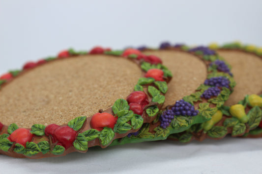 Set of 4 Coasters -  Apple Pattern (2), Grape   Pattern (1); Pear Pattern (1)  Russ Wine Cellar - Berrie and Company  Approx:  3.75” Round  Ceramic With Cork Inlay