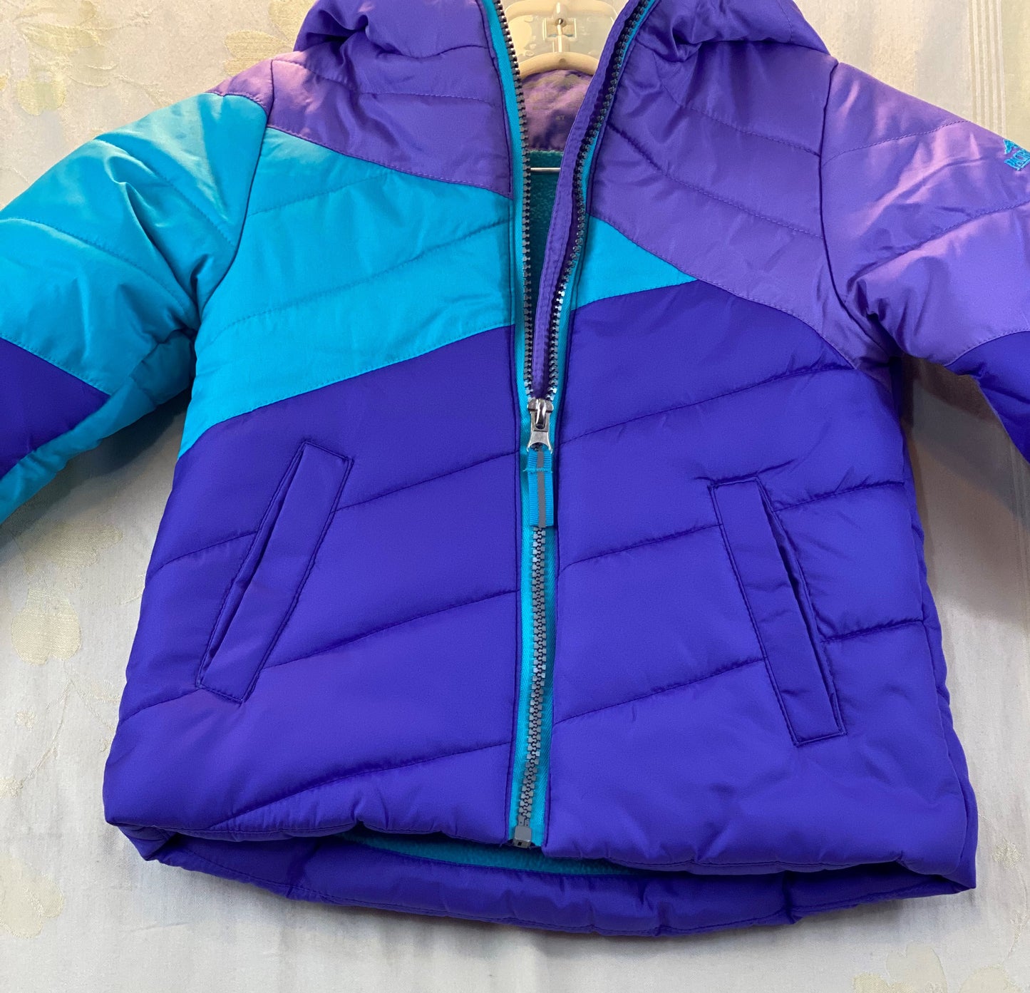 Pre-Owned - Excellent Condition   Girl’s Coat - Size 4-T  Purple & Aqua Color  Attached Hood  Two (2) Front Pockets  16” Shoulder to Bottom;  14” Sleeve;  13’ Across Chest  100% Polyester