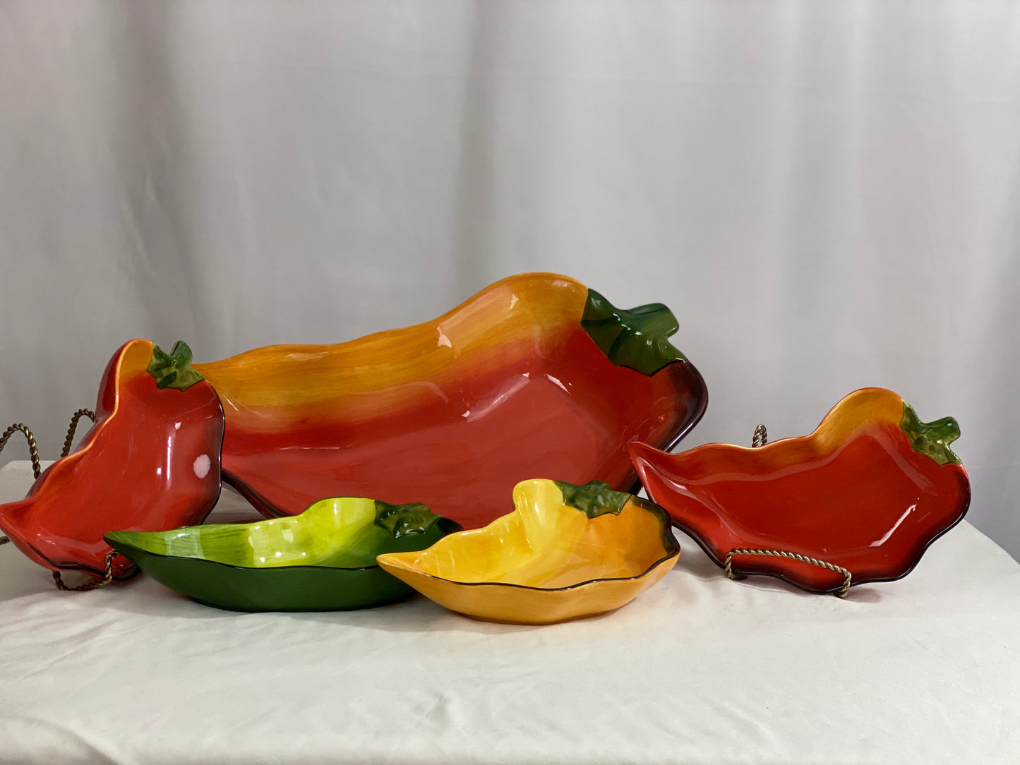 Chili Pepper Serving Set  Clay Art/Ceramic  One (1) Main Dish -- Red/Yellow  Approx 17” L x 8” W  Four Serving Dishes --  2 Red; 1 Yellow; 1 Green                                                                                                                                                                                                                                                                             Approx 9” L x 4 ½ ”W