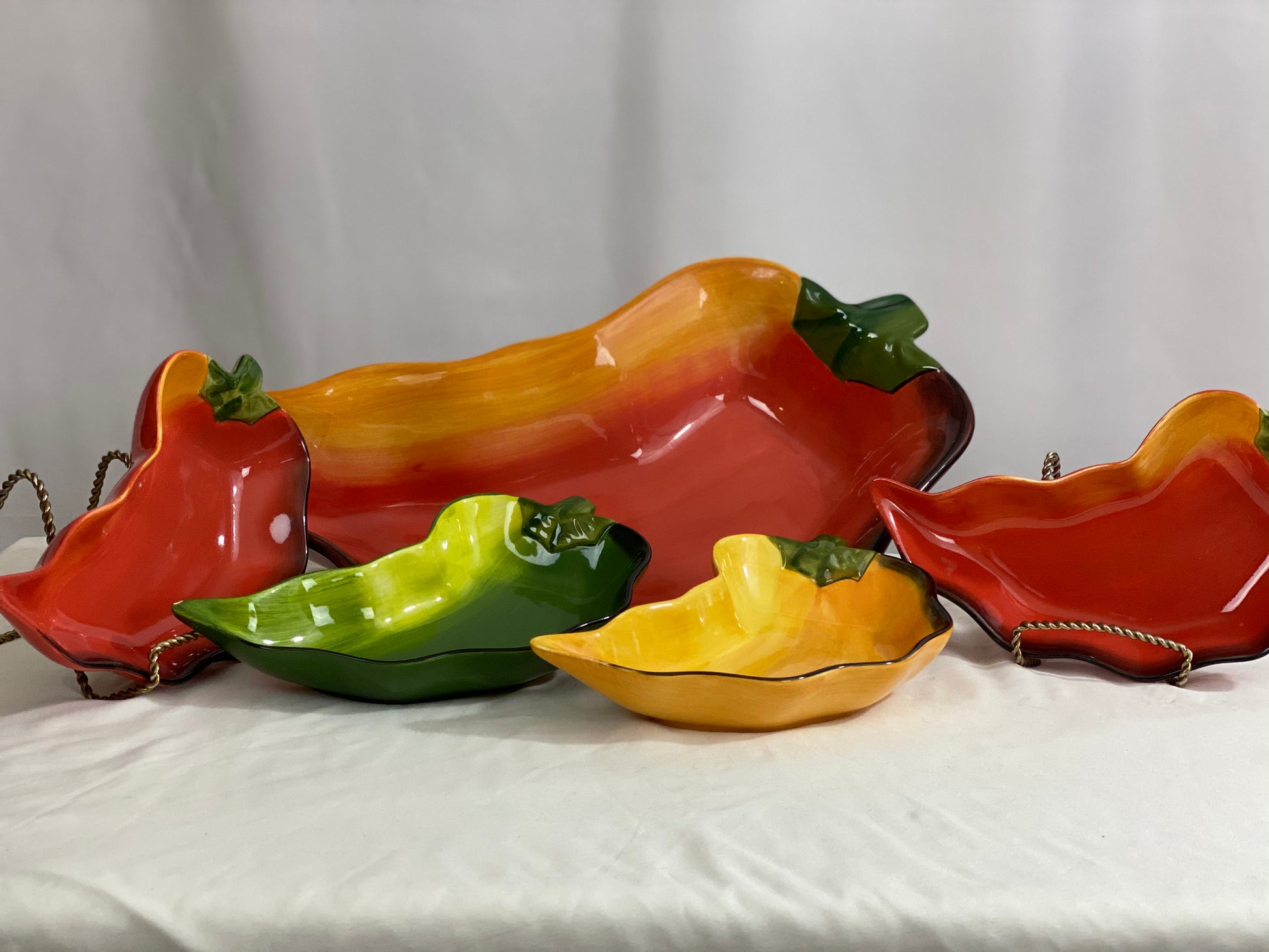 Chili Pepper Serving Set  Clay Art/Ceramic  One (1) Main Dish -- Red/Yellow  Approx 17” L x 8” W  Four Serving Dishes --  2 Red; 1 Yellow; 1 Green                                                                                                                                                                                                                                                                             Approx 9” L x 4 ½ ”W